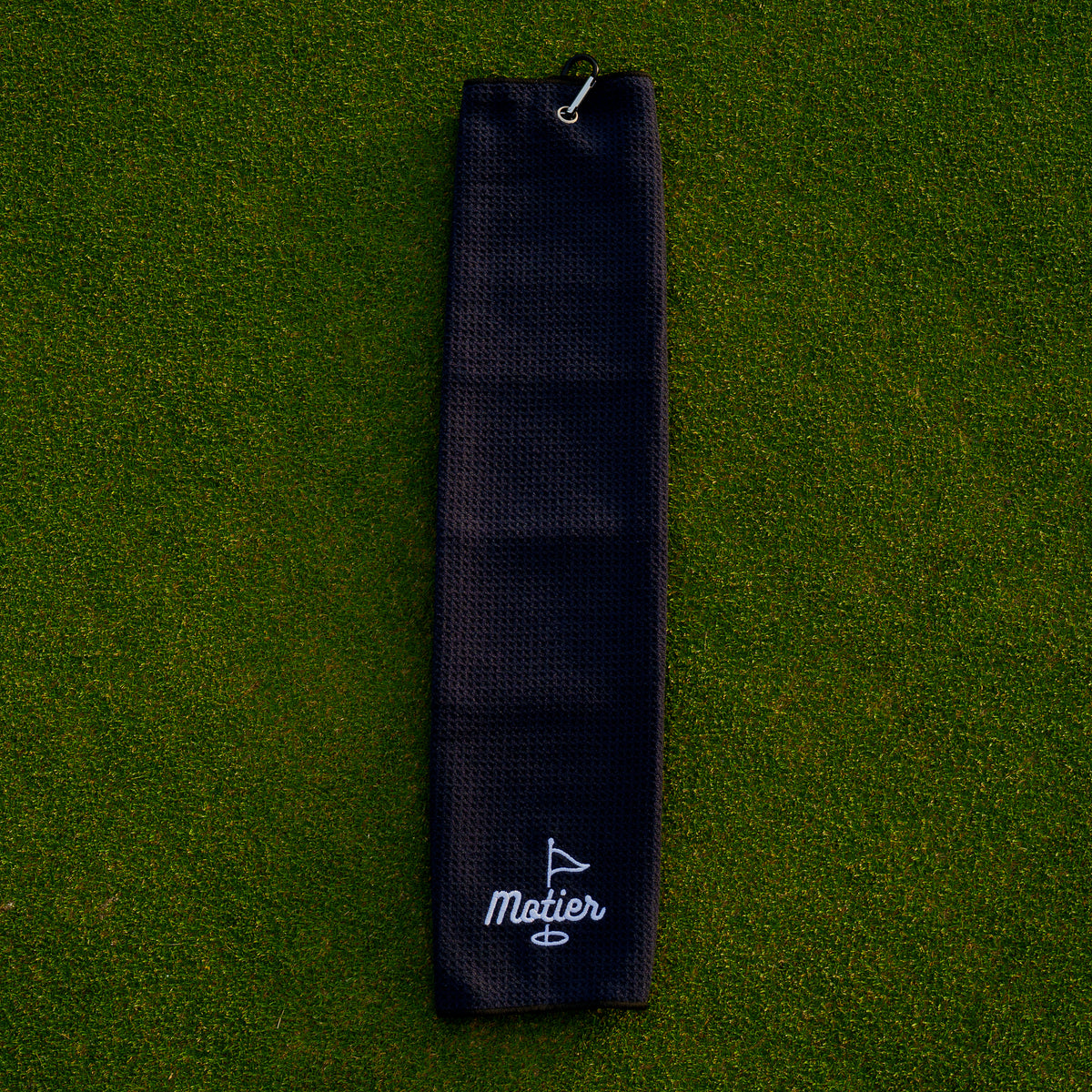 Black microfiber golf towel by Motier Lafayette with branding, shown draped over a golf club for cleaning and drying clubs.