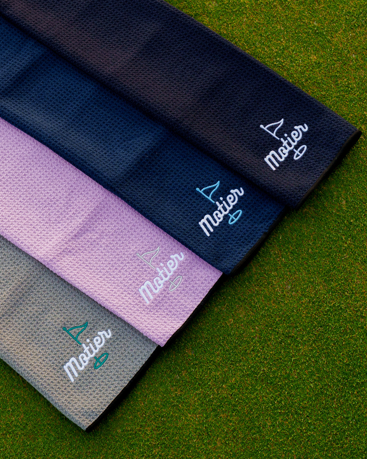 Black microfiber golf towel by Motier Lafayette featuring the "Pin" design, ideal for cleaning golf clubs and balls.