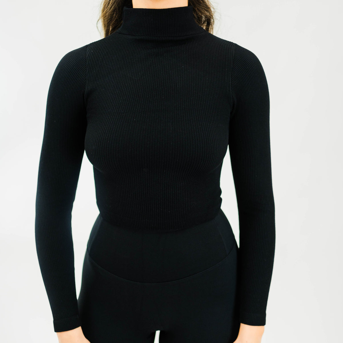 Black women's ribbed mock-neck long-sleeve top by Motier Lafayette, showing close-up of fitted fabric and neckline.