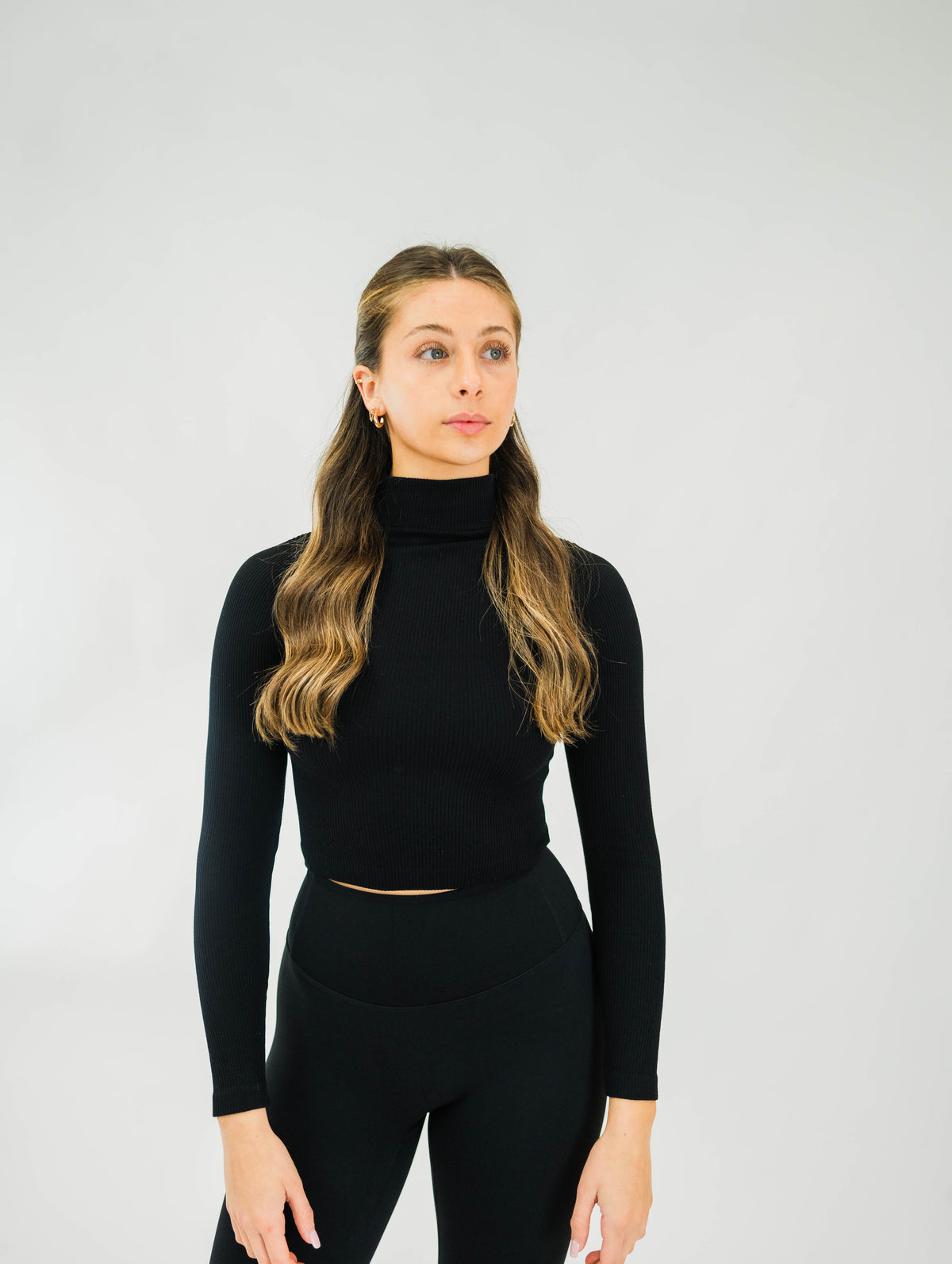 Black women's ribbed mock-neck long-sleeve top by Motier Lafayette, close-up of fitted fabric and neckline detail.