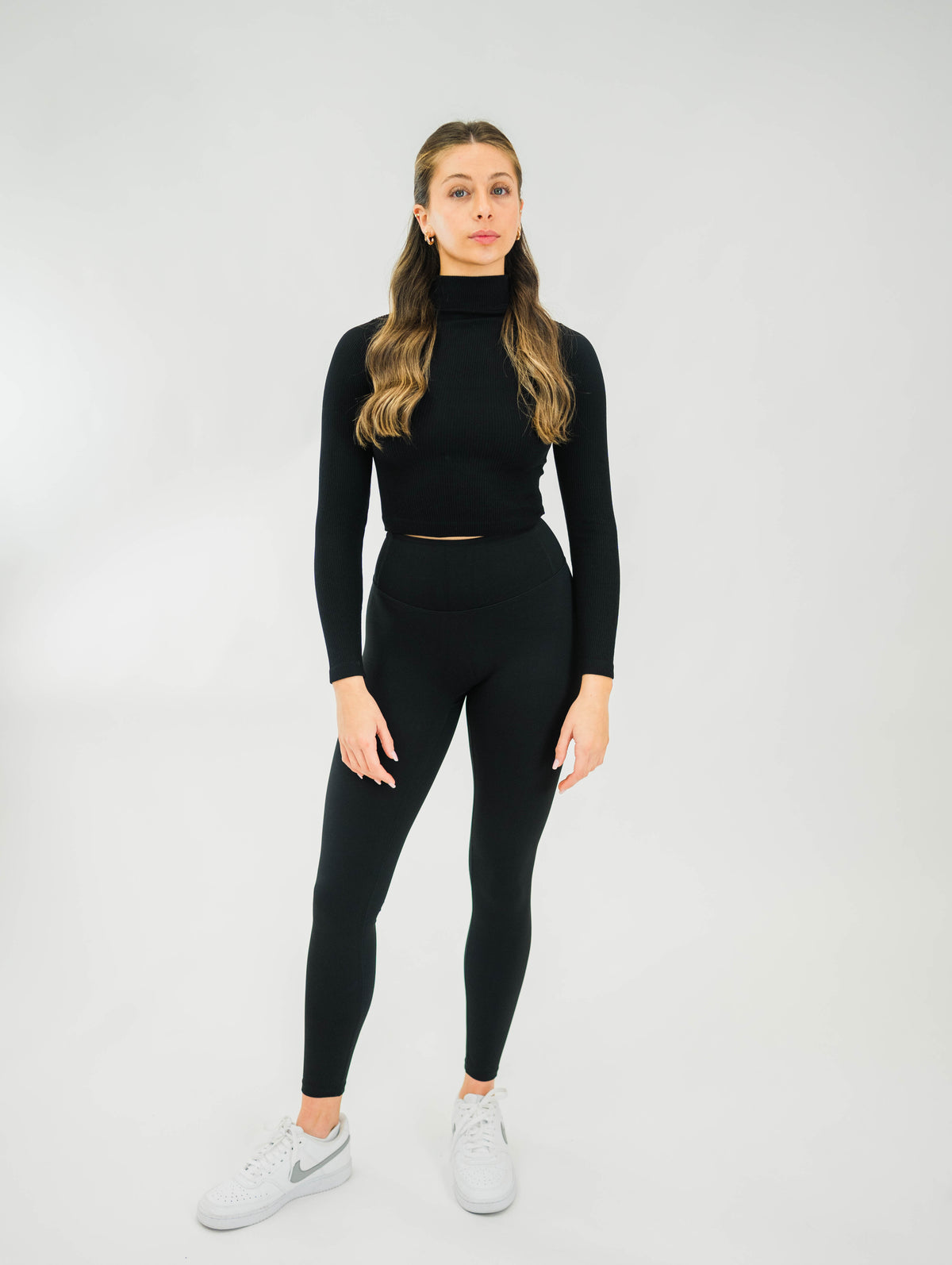 Black ribbed women's mock-neck long sleeve top by Motier Lafayette, close-up showing fabric texture and fitted style.