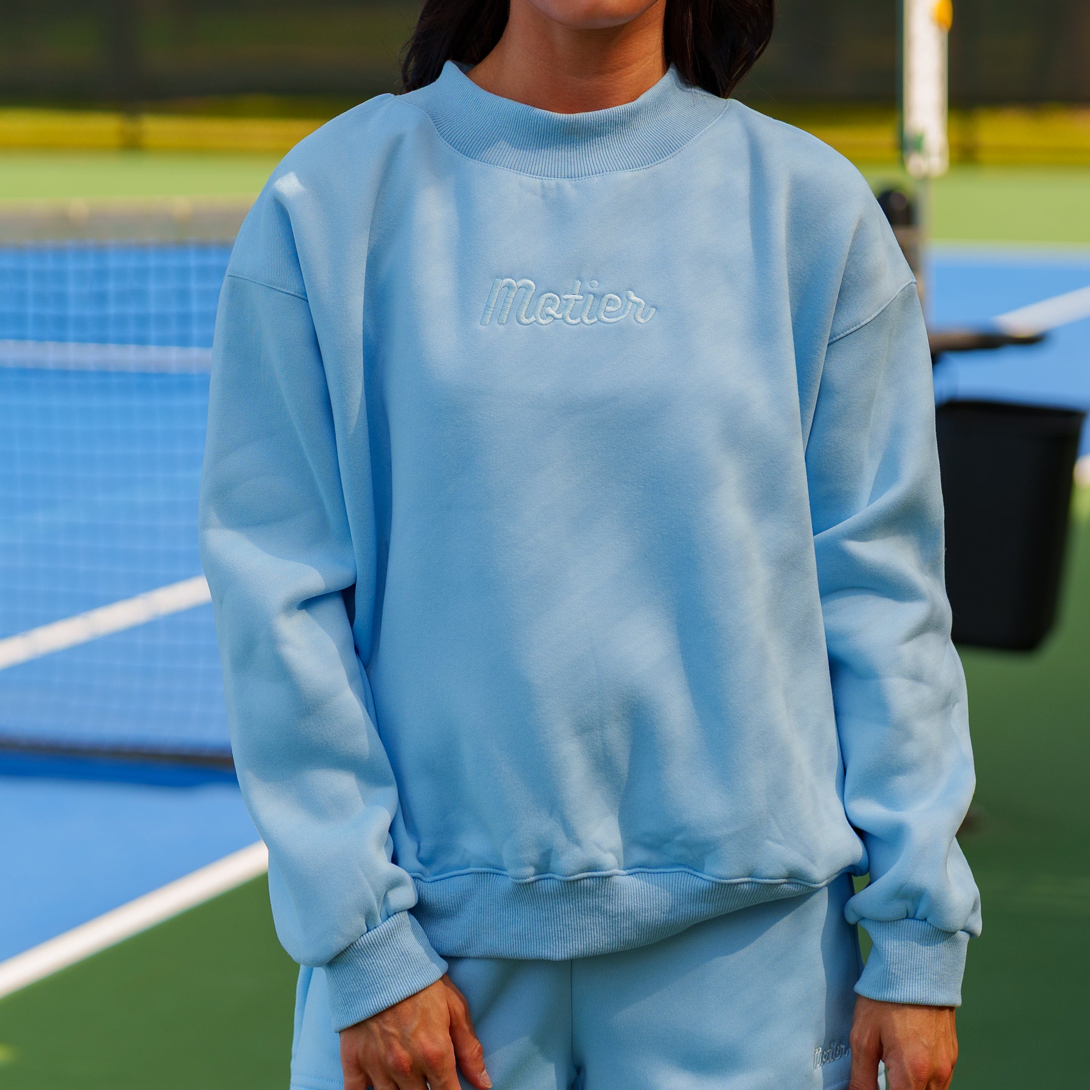 Sky blue The Pin Script Mock Neck sweater by motierlafayette, featuring a fitted silhouette and soft knit fabric.